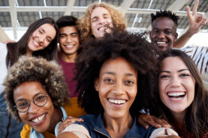 Young African American girl takes a cell phone photo with her multiracial group of friends